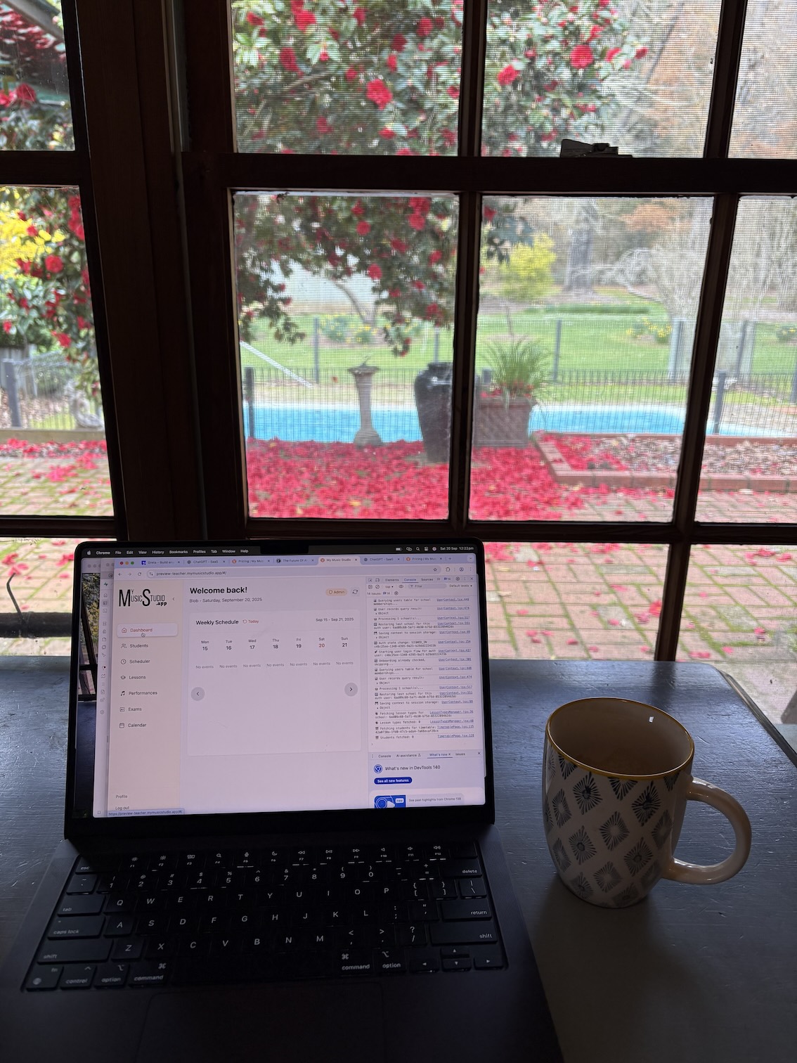 Laptop on a desk with coffee and a sleeping dog in a bright Wandiligong valley setting, symbolizing calm focus and creative work on My Music Studio.