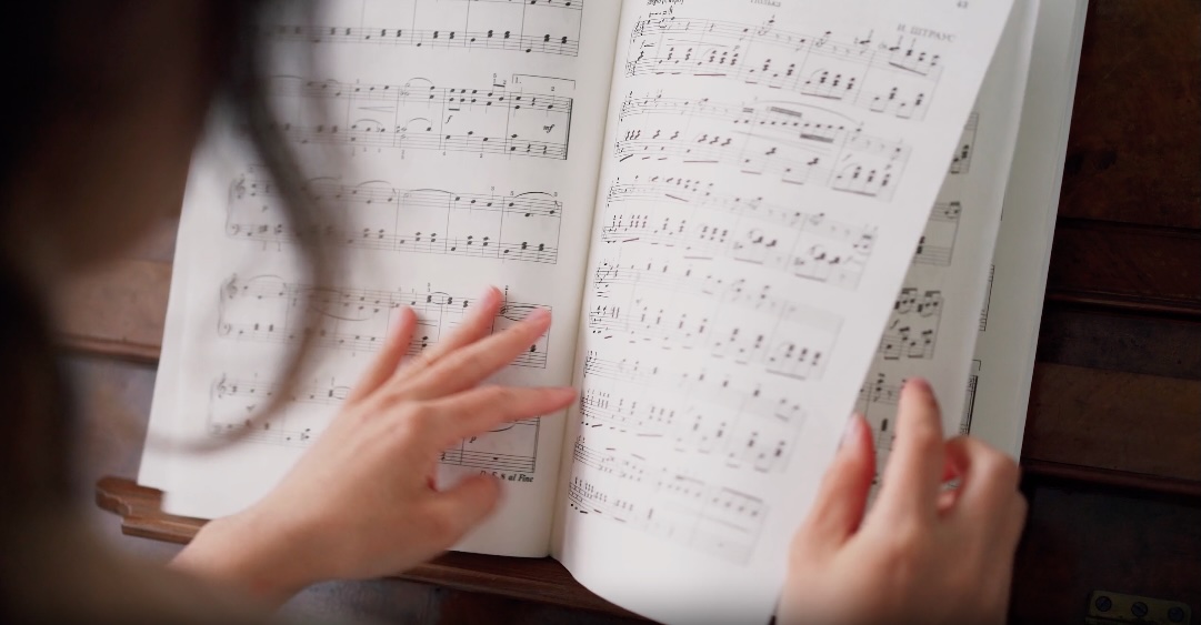 A student looking through sheet music on a piano.